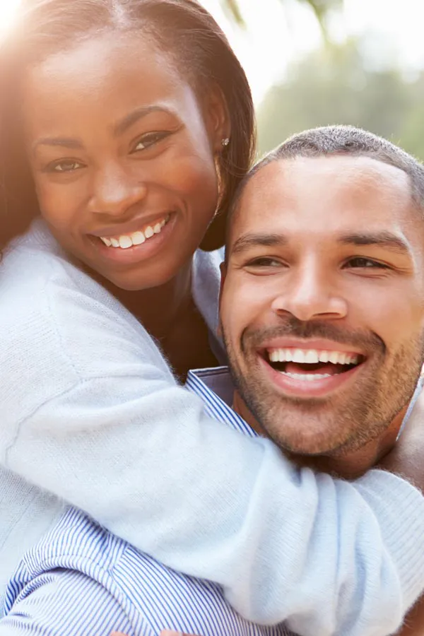 A woman riding on a man's back, both smiling due to help with erectile dysfunction from Tanya Zboril, NP of TBT Medical in Edmonton.