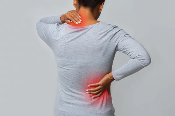 An image from behind of a woman suffering from Fibromyalgia holding her hands on her neck and lower back. Get fibromyalgia care from Tanya Zboril, NP of TBT Medical in Edmonton.