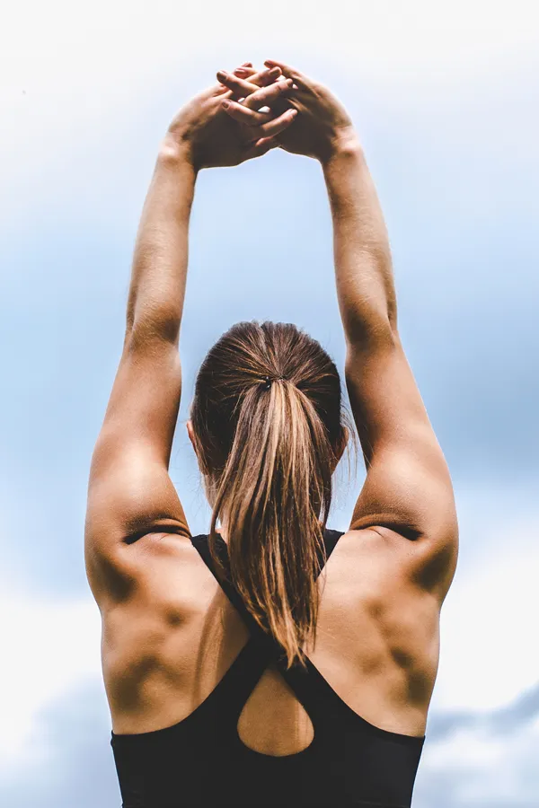 A toned woman seen from behind stretching her arms into the air. Get GLP-1 Weight Loss Injections from Tanya Zboril, NP of TBT Medical in Edmonton.