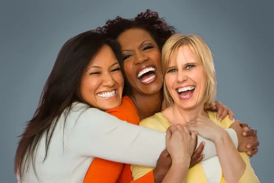 An asian, black, and white woman of middle age hug and laugh. Get insulin resistance treatment from Tanya Zboril, NP of TBT Medical in Edmonton.
