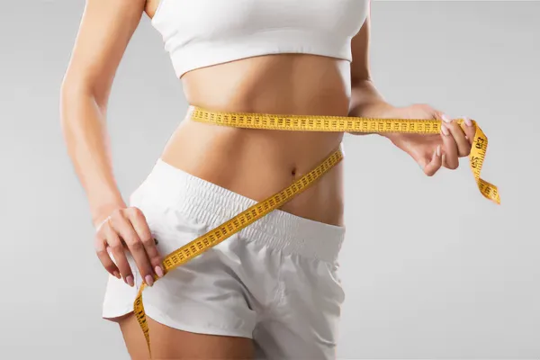 Low-Dose-Naltrexone-for-Weight-Loss-Doctor A woman wraps a measuring tape around her waist to show the success of her Low Dose Naltrexone for Weight Loss treatments from Tanya Zboril, NP of TBT Medical in Edmonton.