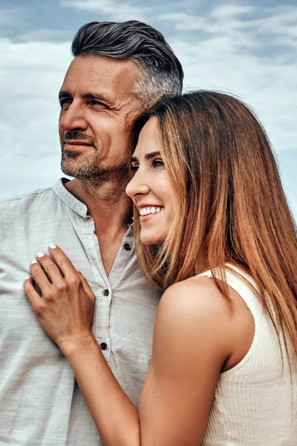 A healthy middle-aged couple look out onto the ocean. Get Medical Genetic Testing from Tanya Zboril, NP of TBT Medical in Edmonton.