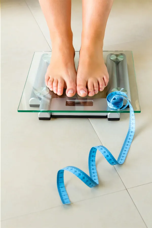 Feet on a scale with a measuring tape for weight loss. Get Ozempic for weight loss from Tanya Zboril, NP of TBT Medical in Edmonton.