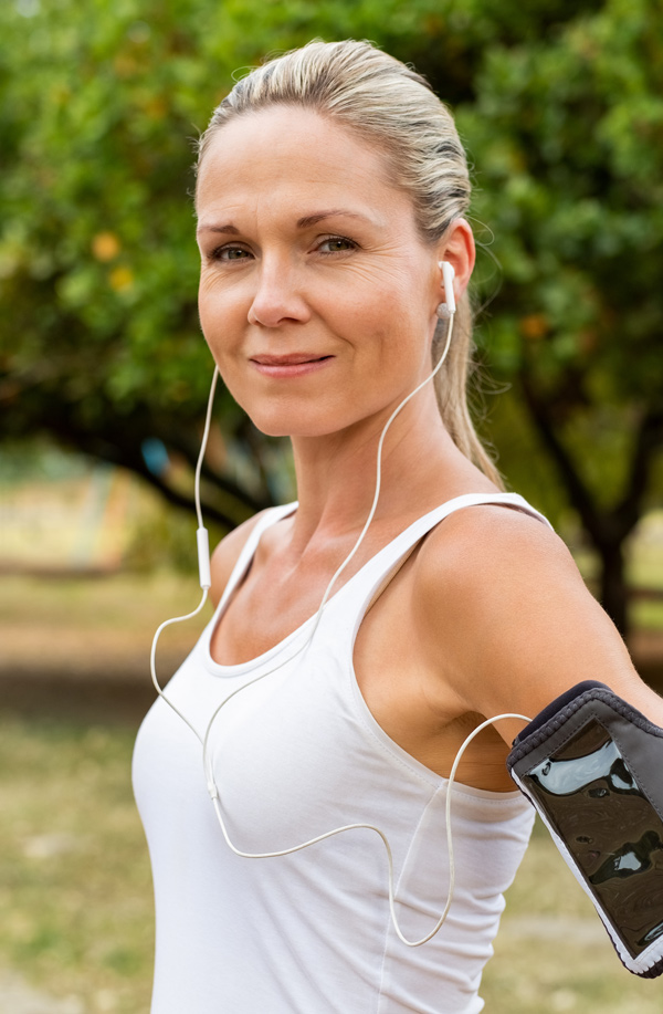 Middle-aged, active woman taking a break to smile at the camera during a run, representing successful Bioidentical Hormones for Fibromyalgia Relief offered by Tanya Zboril, NP of TBT Medical in Edmonton.